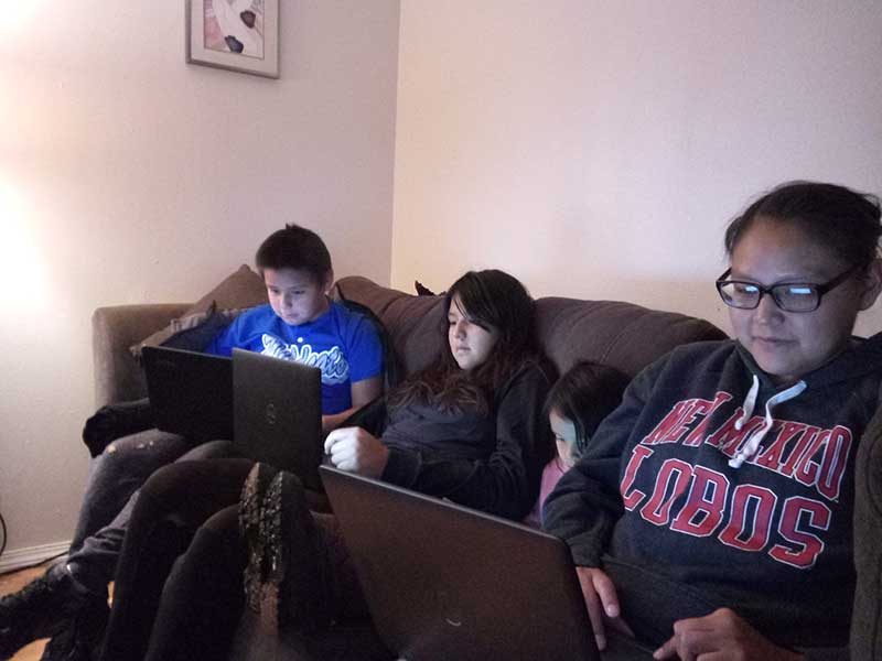 Family sitting at couch working on laptops