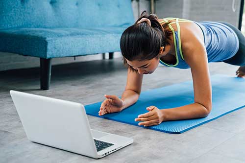 Woman doing yoga watching laptop